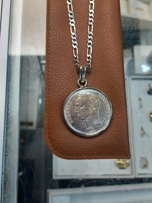 A silver coin mounted as a pendant on a heavy silver figaro chain